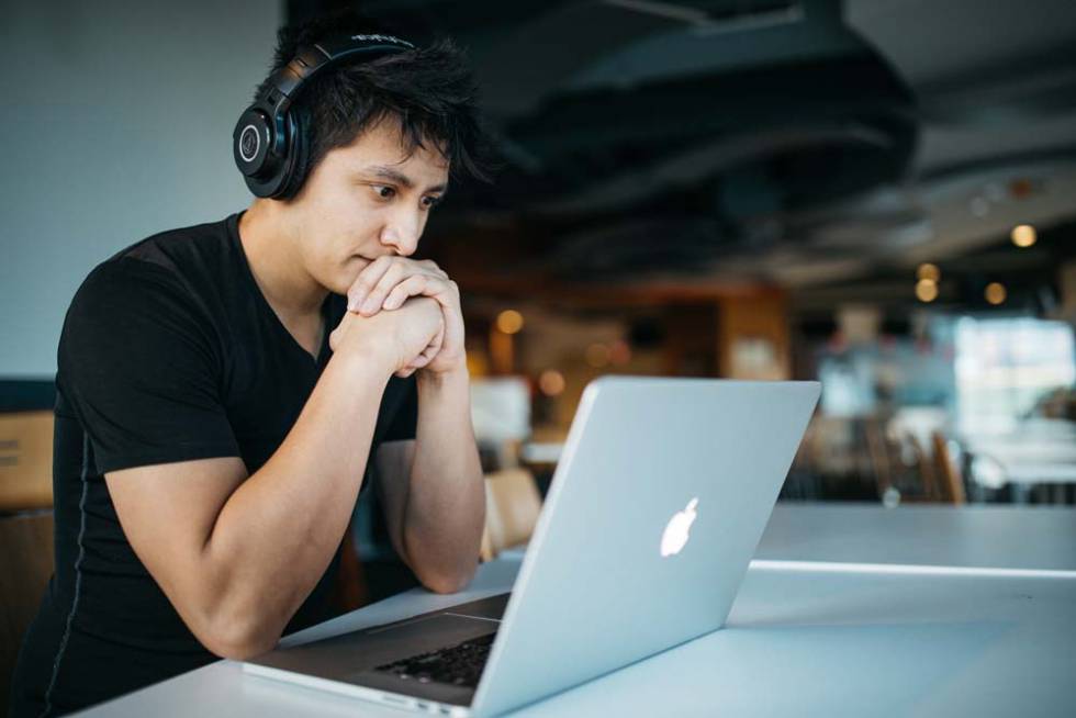 Chico escuchando música en un Apple MacBook