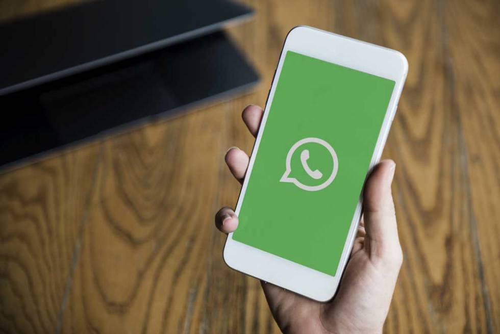 Teléfono con pantalla vede y logo de WhatsApp