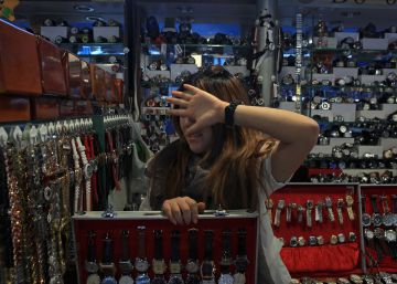 Una vendedora de relojes se tapa la cara en el Mercado de la Seda de Pekín