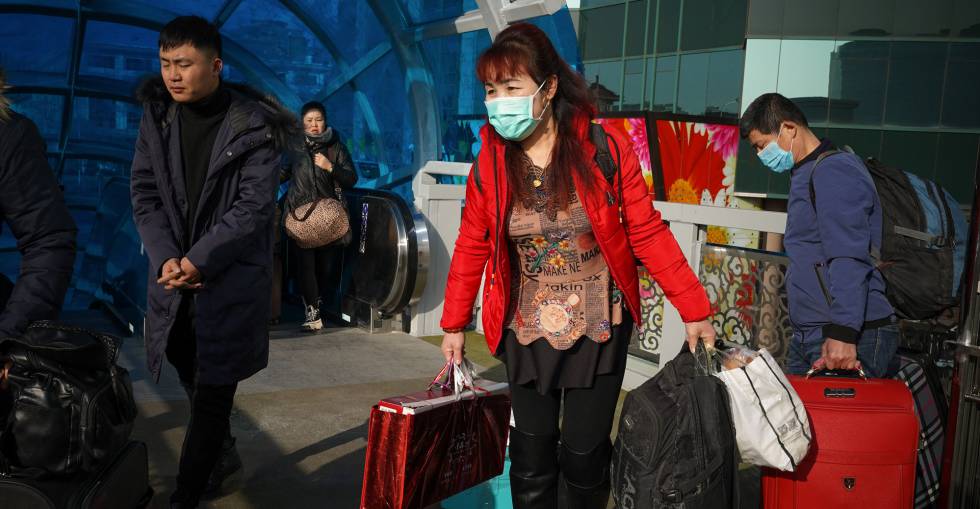 Viajeros dispuestos con mascarillas esperan la salida en la estación de tren de tren de Pekín. 
